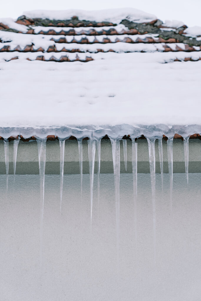 Barrage de glace sur un toit en tuiles avec accumulation de neige et glaçons au bord de la gouttière