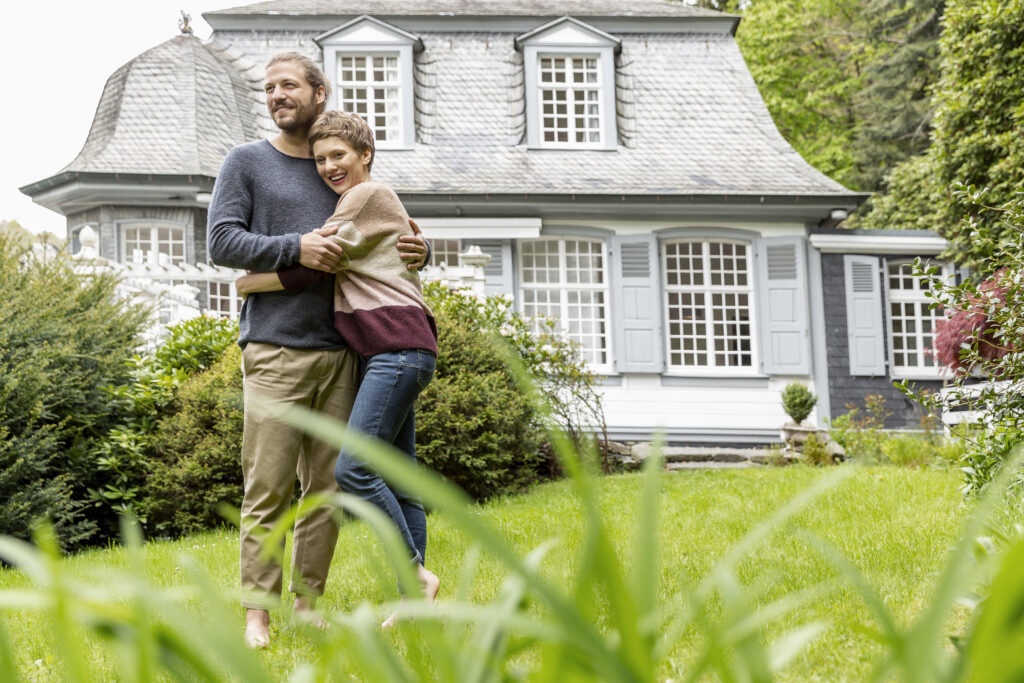 Couple heureux devant leur maison après avoir choisi d'isoler avant l'été