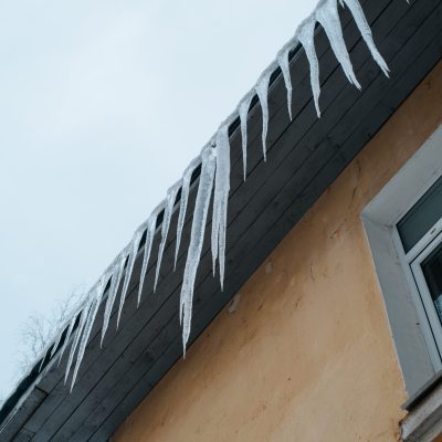Glaçons formés par un barrage de glace pendant le long du soffite d'un toit en hiver
