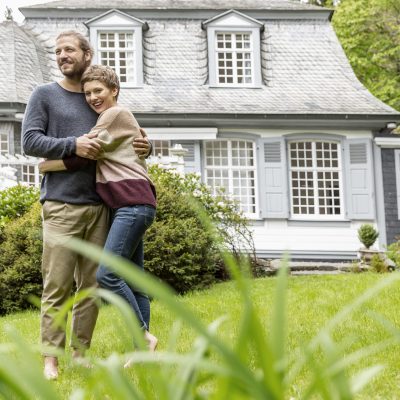 Couple heureux devant leur maison après avoir choisi d'isoler avant l'été